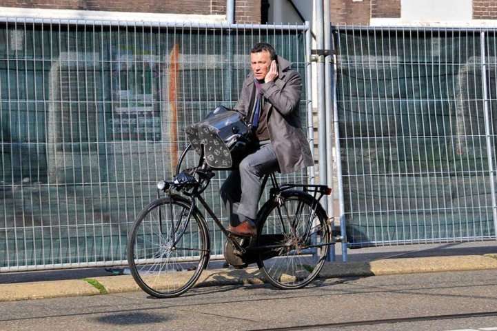 En bicicleta, hablando por el teléfono móvil-celular