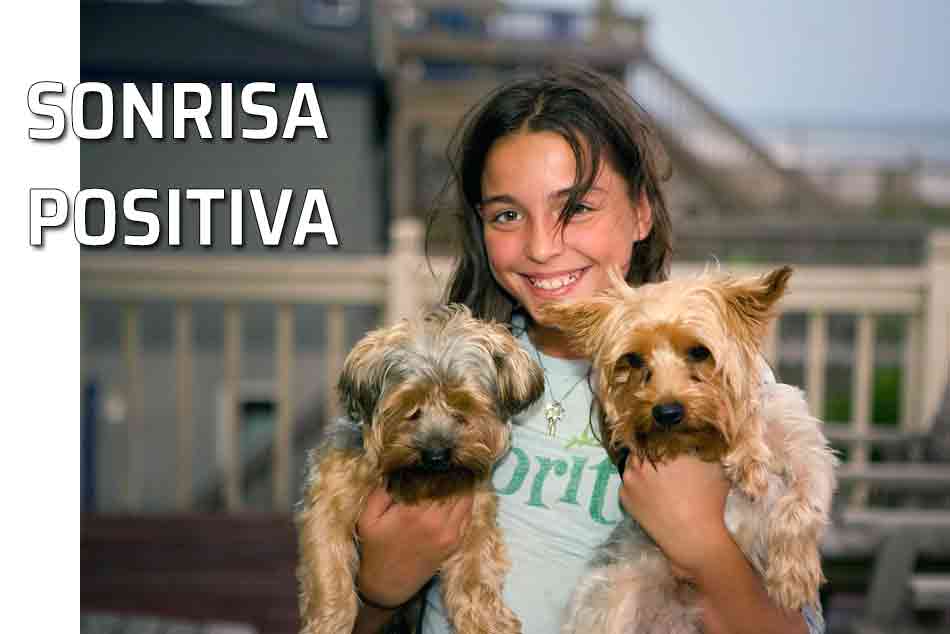 La sonrisa social. Sonreír mejora nuestras relaciones sociales. Jovencita con dos perritos