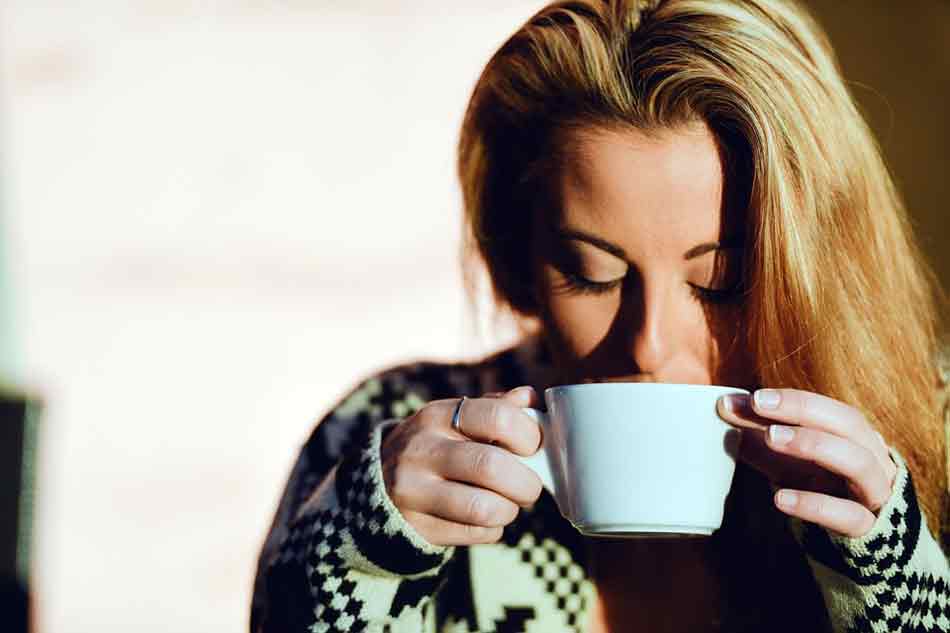 Sujetar una taza con una bebida caliente o fría. Mujer sujeta una taza de café