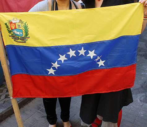 Dos chicas sujetado la bandera de Venezuela.