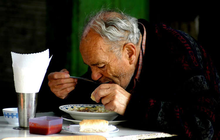 Hombre tomando su comida. Barrio Patronato, Santiago, Chile.