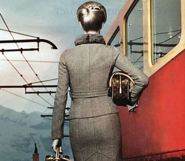 Elegante mujer con maletas en una estación de tren.