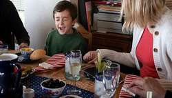 Una madre enseña a comportarse a un niño en la mesa.