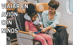 Una madre pone el cinturón de seguridad a su hija en el asiento de un avión
