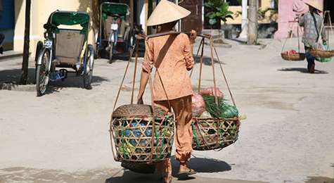 Vietnamita llevando una carga a los hombros.