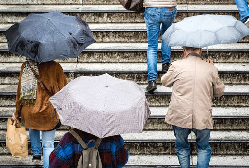 Personas con sus paraguas subiendo unas escaleras.